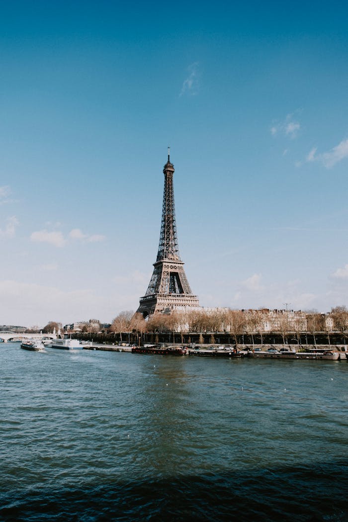 Iconic Eiffel Tower and Seine River under a clear blue sky in Paris, France.