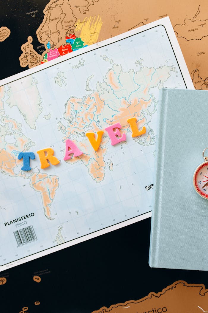 Vibrant travel arrangement featuring a world map, colorful letters, and a compass for adventure planning.